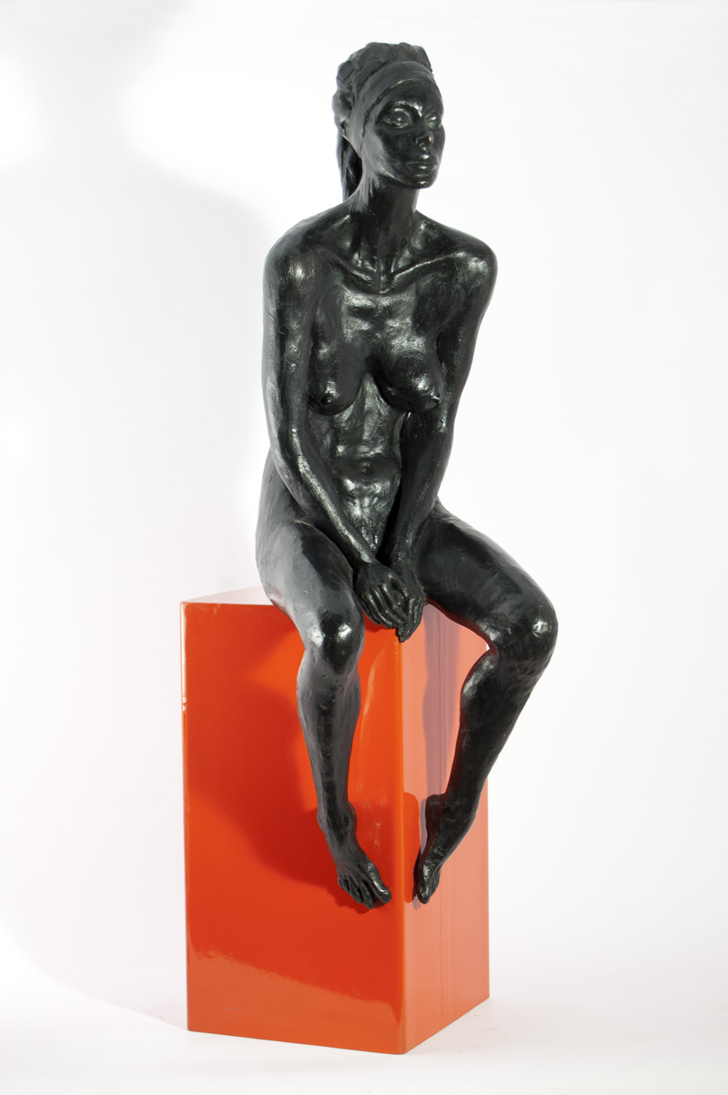 Scultura in bronzo di Lucia Zei che ritrae una donna seduta su un parallelepipedo